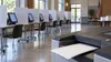 Illustration of an empty polling place with generic voting screens and an unmarked paper ballot entering a scanner