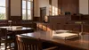 Empty Georgia courtroom with wooden counsel tables, a judge's bench and blank case folders in soft morning light