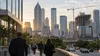Anonymous commuters approach an Atlanta business district with office towers and a construction crane at sunrise.