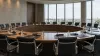 An empty circular conference table prepared with microphones and folders in a modern international meeting room.
