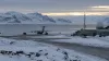 A generic Arctic military airfield beside a frozen fjord, with an unmarked transport aircraft, radar dome and communications tower.