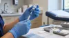 Healthcare worker prepares an unlabeled vaccine syringe in a clinic