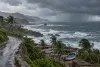 Storm clouds and rough Pacific surf approach a coastal road and secured fishing boats in Mexico.