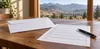 Plain ballot envelope and black pen on a wooden table with Idaho foothills beyond