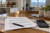Generic health-benefits paperwork, a blank smartphone, eyeglasses and a pen on a kitchen table in an Idaho home