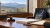 A judge’s gavel and legal papers on a desk beside a child’s backpack, with Idaho mountains visible through a window