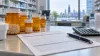 Unbranded prescription bottles, a claim form, pen and calculator on a pharmacy counter