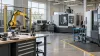 Conceptual view of an empty advanced-manufacturing training lab with a robotic arm and CNC equipment.