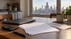 A calculator, blank loan papers and a plain envelope on a kitchen table with a muted Illinois city skyline in the distance.