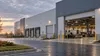 A modern advanced-manufacturing facility with loading bays and steel-processing machinery visible inside.