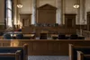 An empty wood-paneled appellate courtroom illuminated by soft morning light, shown as a restrained symbolic image.