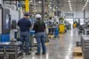Illustrative view of two workers reviewing equipment on an unbranded manufacturing floor