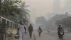 Residents wearing protective masks walk through dense wildfire haze on an Indonesian city street