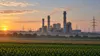 Illustrative view of a modern gas-fired power station and transmission lines across Midwestern farmland.