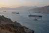 Oil tankers move through the Strait of Hormuz in calm morning light.
