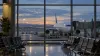 An empty airport gate at predawn with a passenger jet parked outside the terminal windows