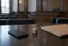 Unbranded smartphone, wooden toy block and legal folder on a courtroom counsel table