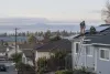 Solar installers work on a home rooftop above a neighborhood and community solar array.