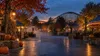 Empty autumn amusement park midway with a wooden roller coaster at dusk
