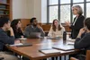Law students and a professor in a sunlit seminar room discussing legal reasoning around a table