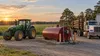 An unbranded farm tractor and logging truck beside a plain fuel tank in a Louisiana agricultural field at sunset.