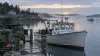 A lobster boat beside stacked traps at a quiet Maine harbor at dawn