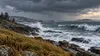 Conceptual storm waves approaching a rocky Maine coast beneath dark autumn clouds