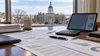 Budget documents, a calculator and abstract charts overlooking an Annapolis statehouse