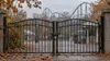 Conceptual locked amusement-park gates with an unbranded roller-coaster silhouette beyond them on an overcast autumn morning
