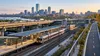 Conceptual Massachusetts transportation corridor with commuter rail, station platforms, highway bridge and separated bicycle path.