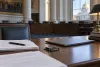 Closed laptop, policy papers and a circuit board on a desk in a stately government hearing room