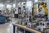Robotic arms and precision metal components inside a modern advanced-manufacturing facility.