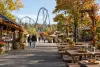 Conceptual autumn amusement park midway with picnic tables, pretzels and a generic roller coaster in the background.