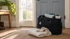 Nurse home-visit bag beside an infant blanket near a front door in soft morning light