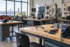 An empty technical training classroom with workbenches, tools and electrical equipment.