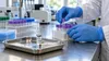 A public-health laboratory professional organizes specimen tubes beside an unlabeled vaccine vial and capped syringe.