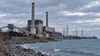 Conceptual editorial image of an aging coal-fired power station beside a Great Lakes shoreline in Michigan.