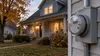 Electric meter beside a warmly lit Michigan home in early autumn