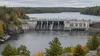 Hydroelectric dam and reservoir bordered by Michigan forest under overcast skies