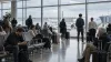 Travelers wait near airport departure gates during a widespread air-traffic disruption.