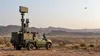 Unmarked mobile counter-drone radar vehicle tracking a small training drone over desert terrain
