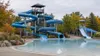 Quiet outdoor water slides and a still pool surrounded by early autumn trees