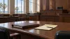 Illustrative empty Gulf Coast courtroom with a closed case folder and legal pad on a wooden table