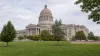 A distant view of the Missouri State Capitol across a green lawn in soft morning daylight