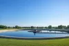 A clean circular municipal wastewater clarifier in a quiet Midwestern landscape.