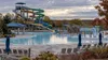 Empty outdoor water slides and pool framed by autumn foliage after the summer season