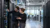 Two engineers inspect server equipment in a modern high-performance computing data center.