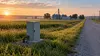 Rural Nebraska road beside communications infrastructure and farm fields at dawn.