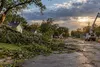 Fallen tree branches and utility crews working along a Nebraska residential street after a windstorm