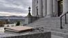 Granite courthouse steps beside a closed file folder and reading glasses under an overcast New Hampshire sky.